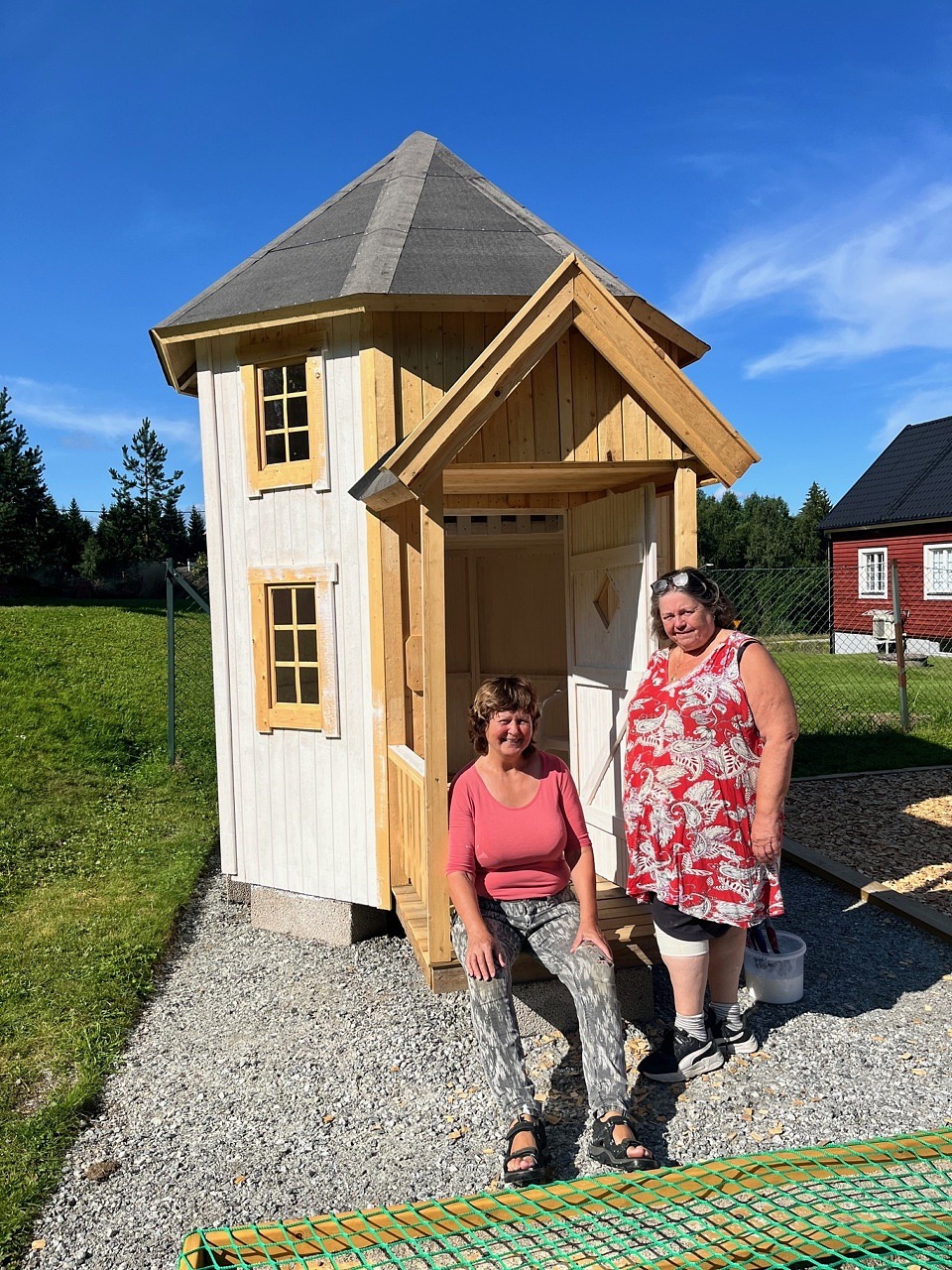 Gunilla och Monika står framför Muminhuset. 