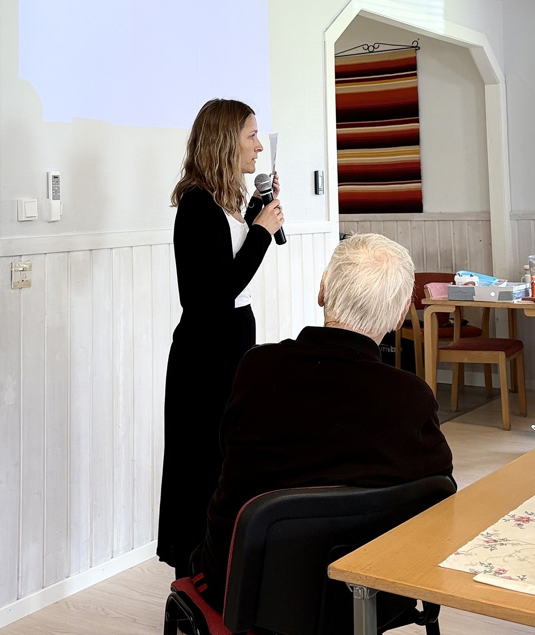 Evelina Andersson från biblioteket pratar i en mikrofon. Man ser henne från sidan.
