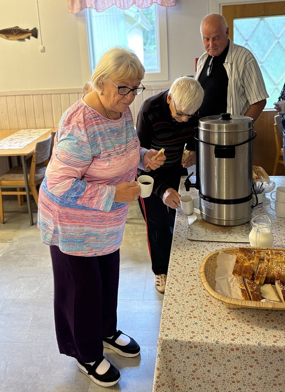 Tre deltagare står i kö för att ta fika.