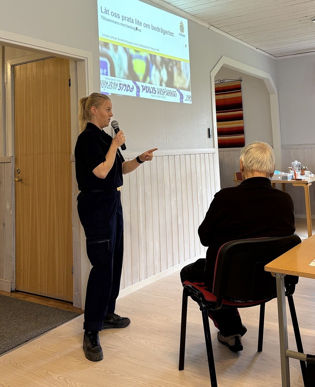 Linnea Löfblad från polisen pratar i en mikrofon och tittar ut där deltagarna sitter.